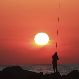 Meer Sonnenuntergang und ein Fischer